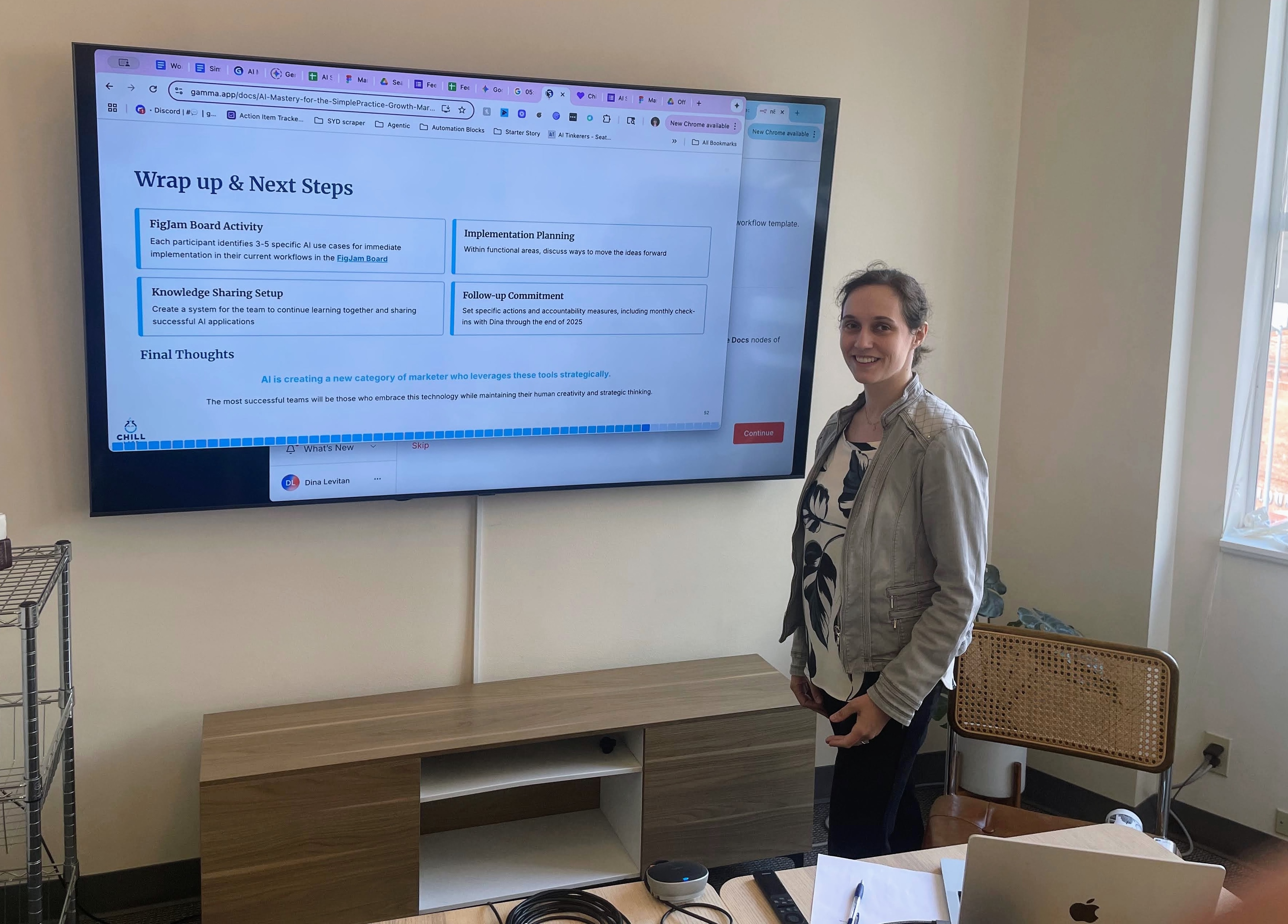 Dina Levitan facilitating an AI training workshop, standing in front of a presentation screen showing implementation planning and next steps for AI adoption